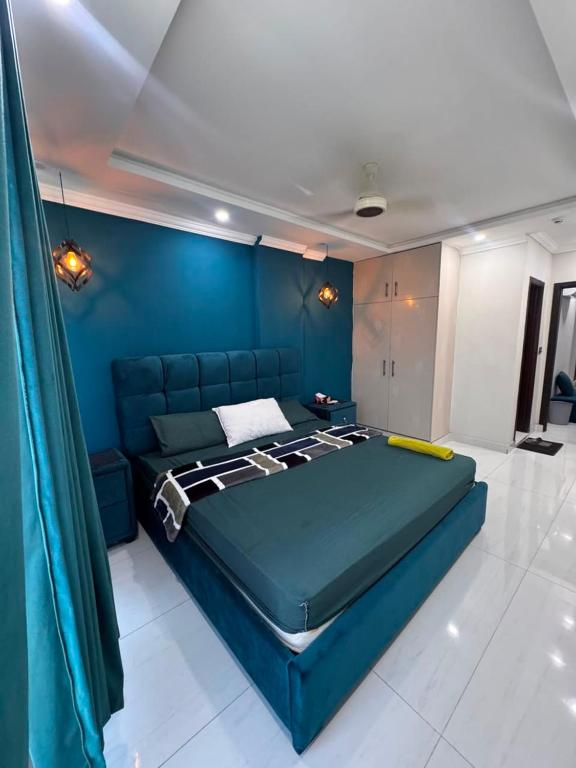 a blue bed in a room with a blue wall at Shazi Heights in Lahore