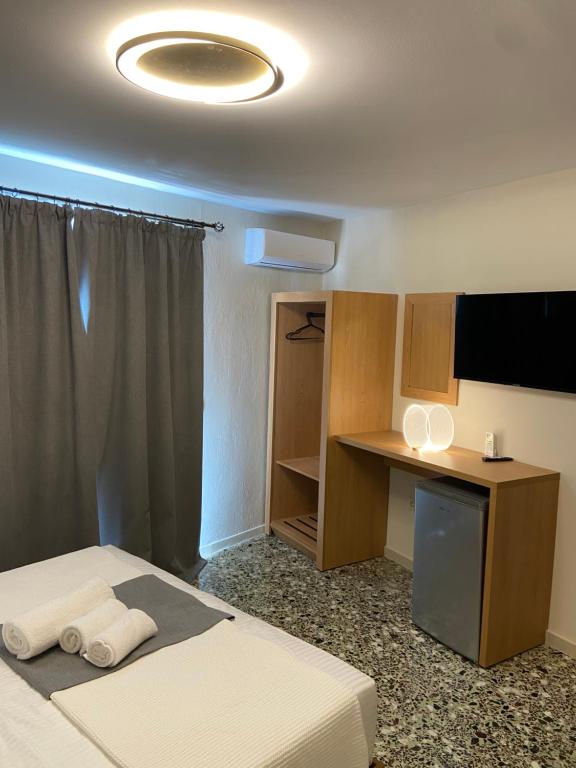 ein Zimmer mit einem Bett, einem Schreibtisch und einem Fernseher in der Unterkunft Old Parga Studios in Parga