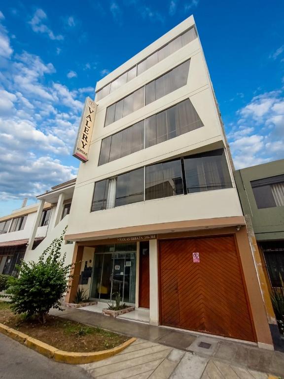 a tall white building with a brown garage at Hospedaje & Minidepas VALERY in Trujillo