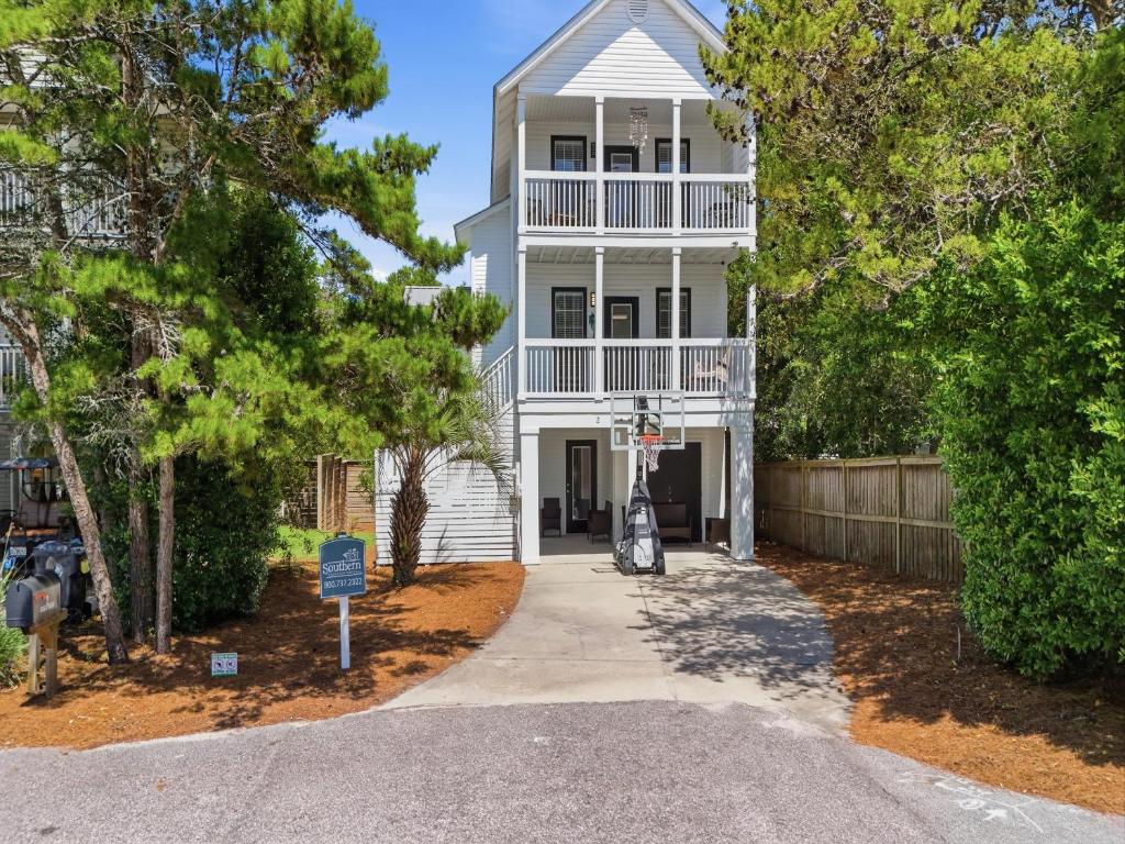 a white house with a fence and trees at Dune Our Thing in Blue Mountain Beach