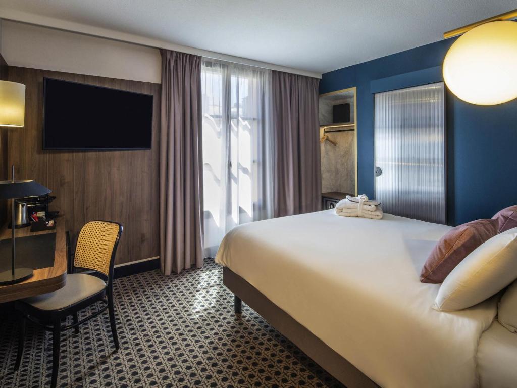 a hotel room with a large bed and a desk at Mercure Versailles Chateau in Versailles