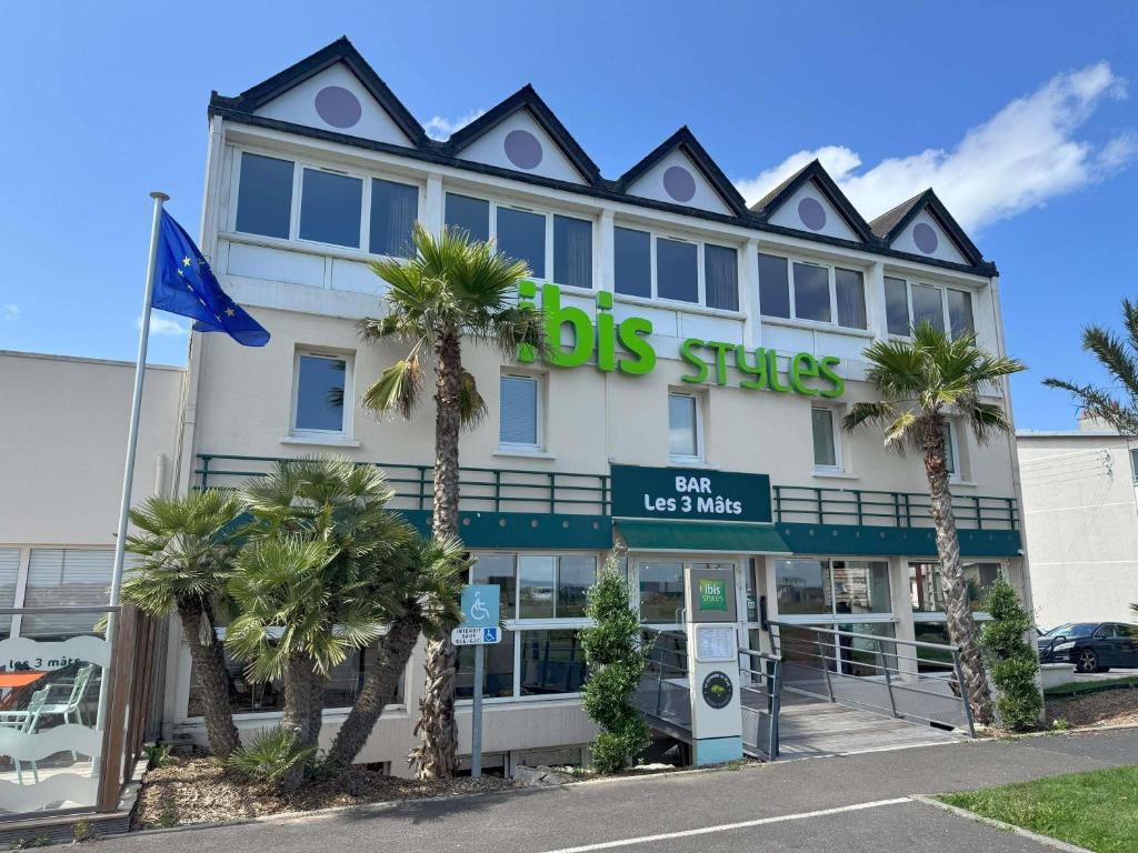a building with palm trees in front of it at ibis Styles Ouistreham in Ouistreham