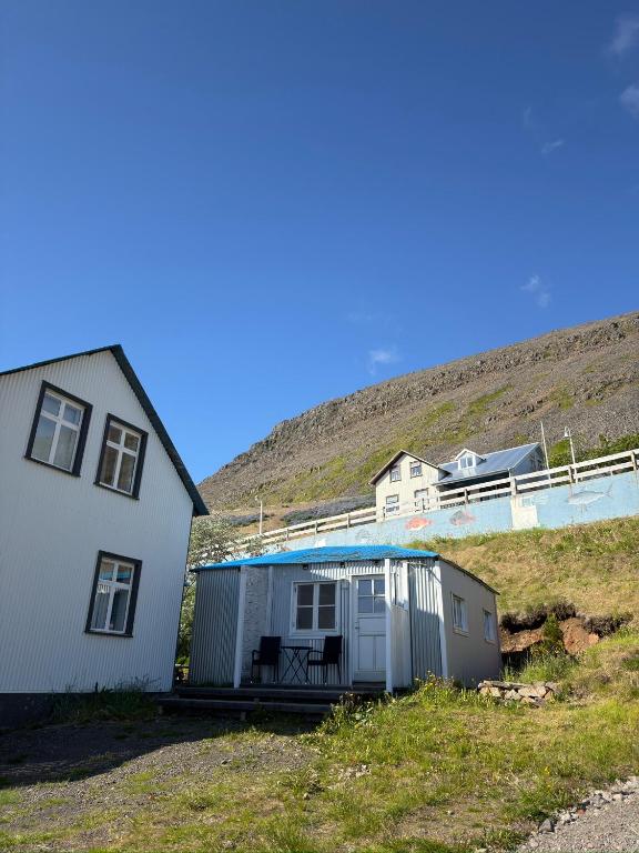 a small house next to a white house and a hill at Krókur Guesthouse in Patreksfjörður