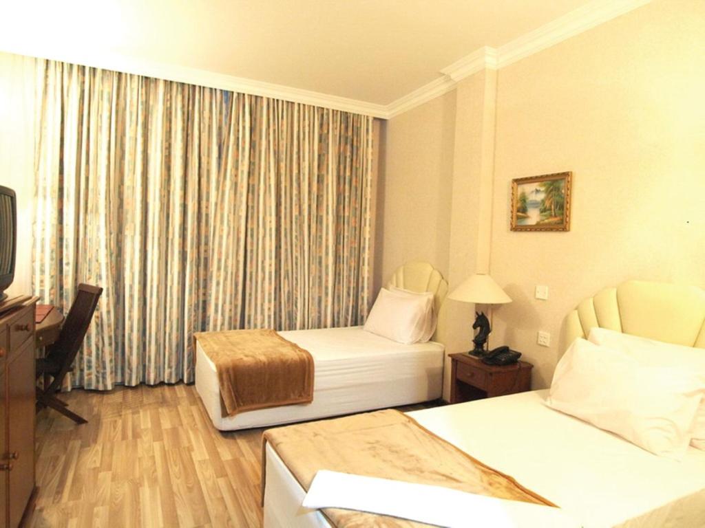a hotel room with two beds and a television at Jeruton Hotel in Kampong Jerudong