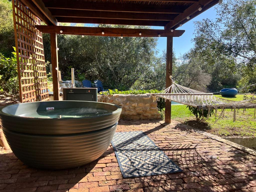 a large tub sitting on a patio with a hammock at Mountain Cabin private hot tub and swimming pool in Wolseley