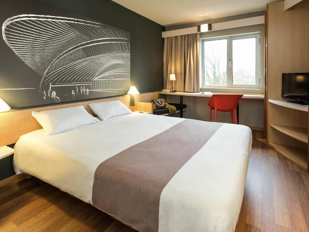 a hotel room with a large bed and a television at ibis Liège Seraing in Boncelles