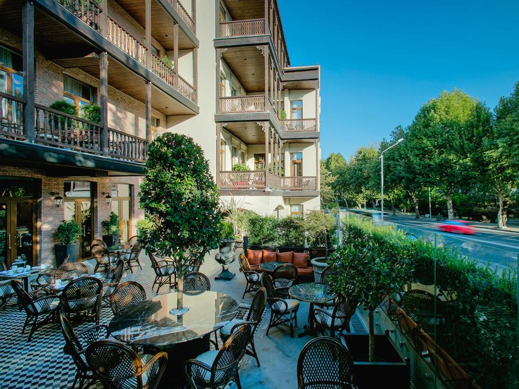 an outdoor patio with tables and chairs and a building at Museum Hotel in Tbilisi City