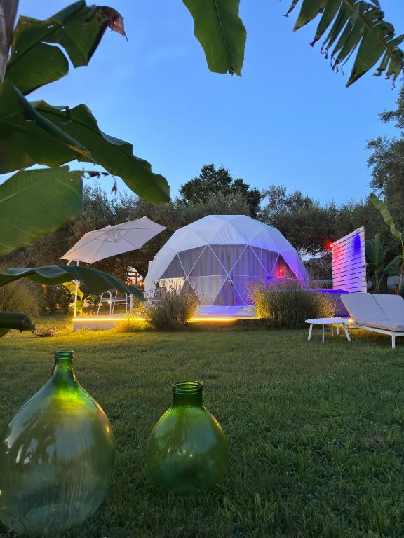 two green vases sitting in the grass with a tent at La Fontana Glamping in Caria