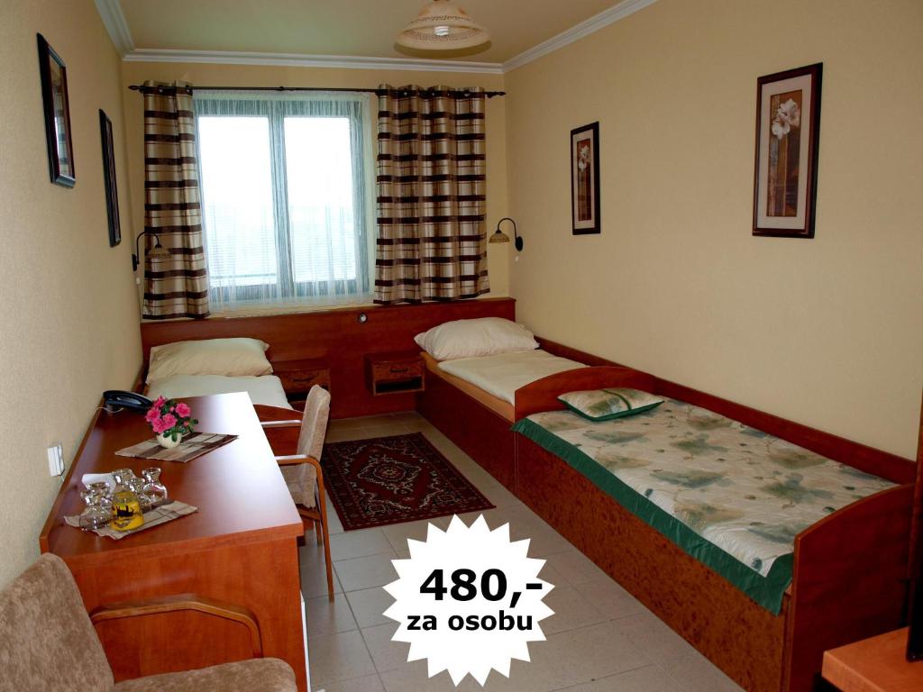 um quarto com 2 camas, uma secretária e uma mesa em Hotel Relax u Drsů em Tábor