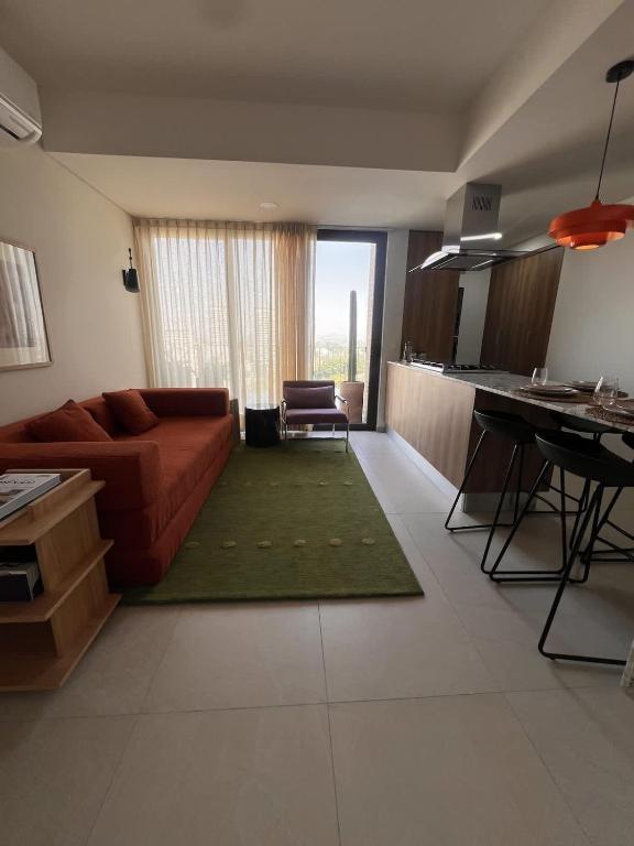 a living room with a red couch and a green rug at Visa Trip Cozy Stay in Guadalajara
