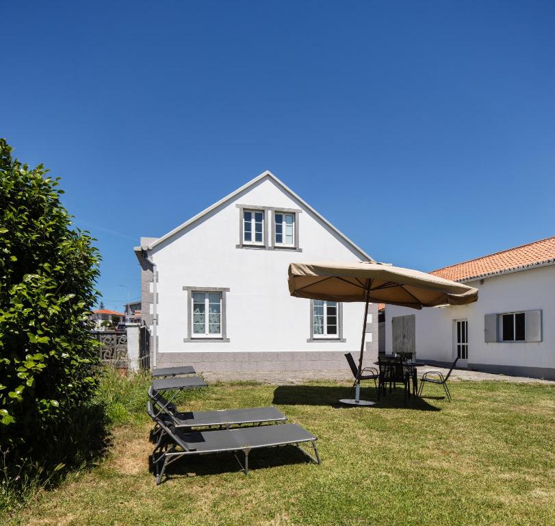 a white house with a table and an umbrella at Casa Raxón Ferrol in Ferrol