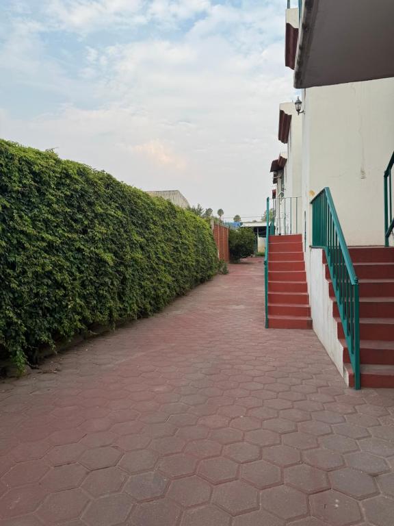 a brick sidewalk next to a building with a green fence at Habitación 11 Posada Itzel in Oaxaca City