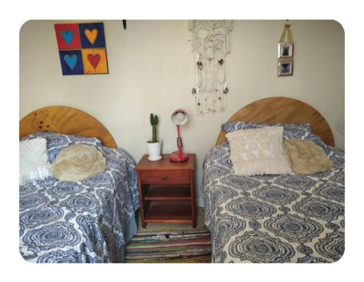 a bedroom with two beds and a table with a night stand at Lamaison in Talca