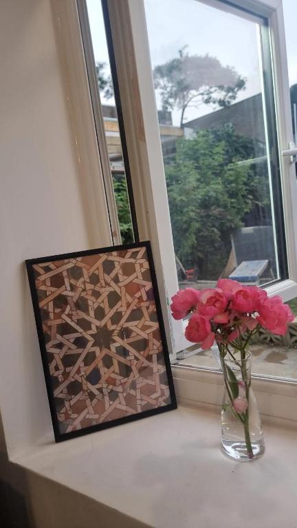 a picture and a vase with flowers in a window at lovely Studio Flat in The Hyde