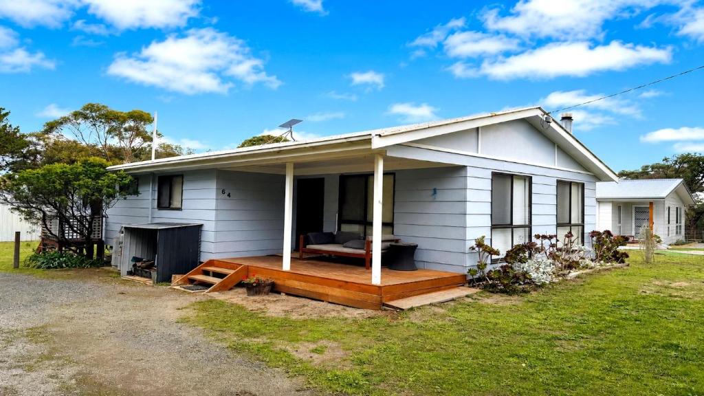 a white house with a large wooden deck at Blue Bay Escape in Venus Bay