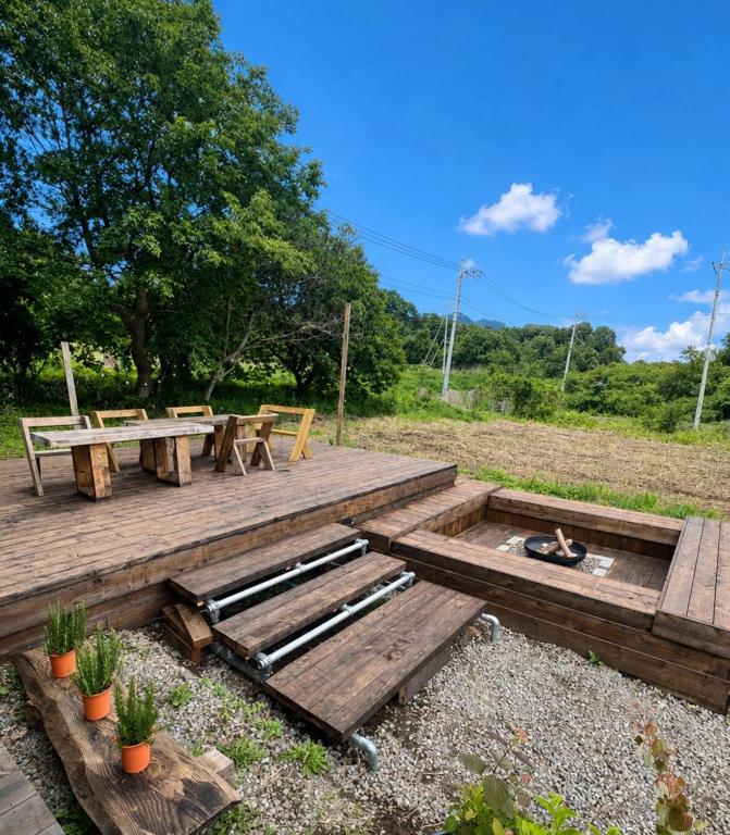 a wooden deck with a picnic table and a fire pit at Vacation Rental NENBA in Hokuto