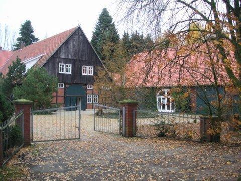 uma cerca em frente a uma casa com um celeiro em Golfhotel Blaue Ente em Warendorf