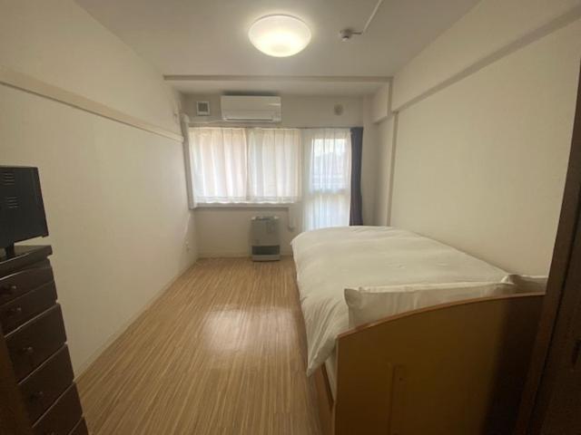 a small bedroom with a bed and a window at メープル桑園駅311 in Sapporo