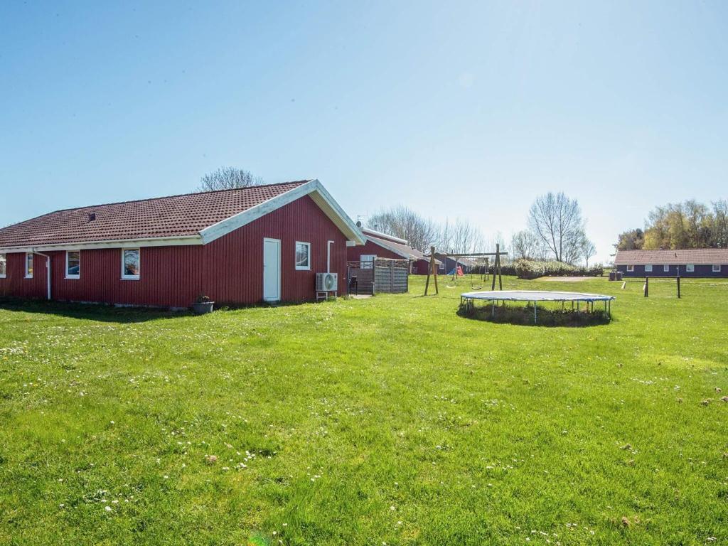 a red barn in a field next to a building at 4 star holiday home in Nordborg in Nordborg