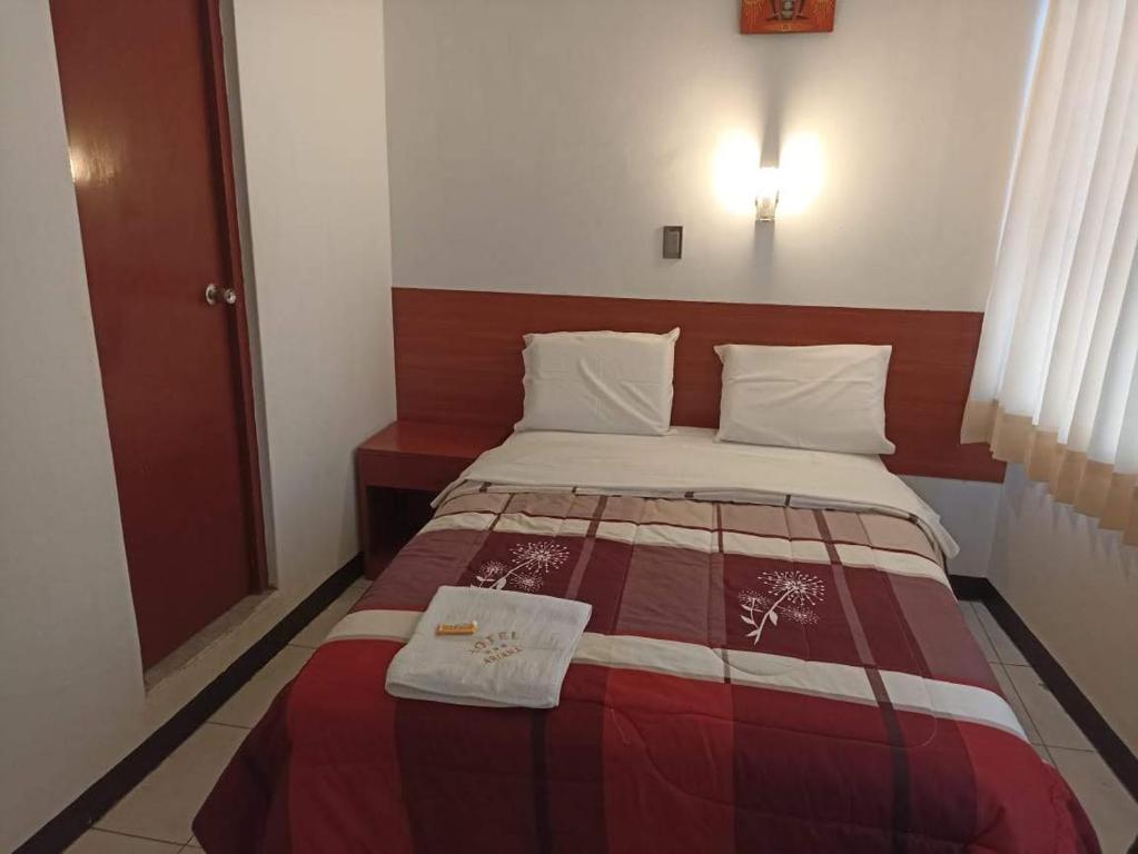 a bedroom with a bed with a red and white blanket at hotel esmeralda in Chiclayo