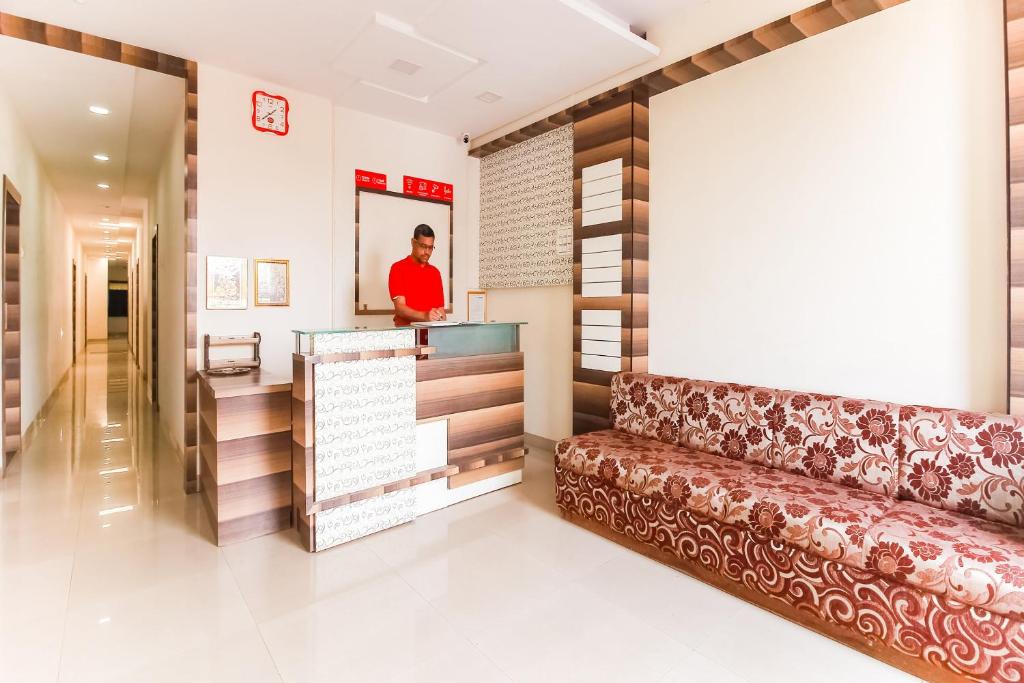 a man standing at a counter in a lobby with a couch at Hotel O Unique Inn in Dhule