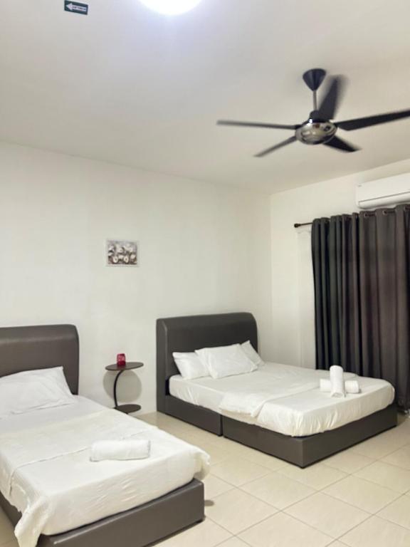 two beds in a room with a ceiling fan at FE Homestay in Tawau