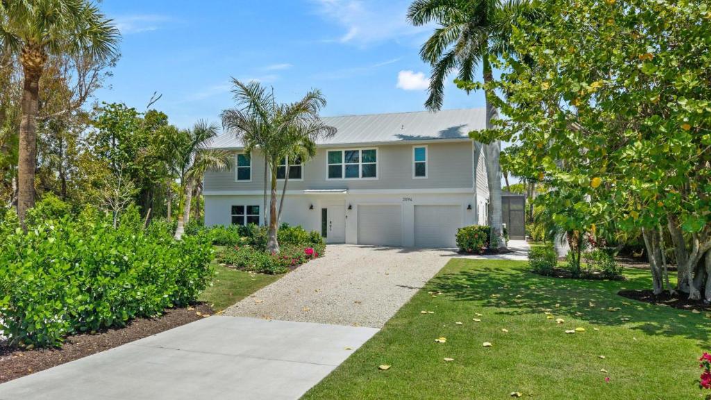 a white house with palm trees and a driveway at Seaside Rendezvous in Sanibel