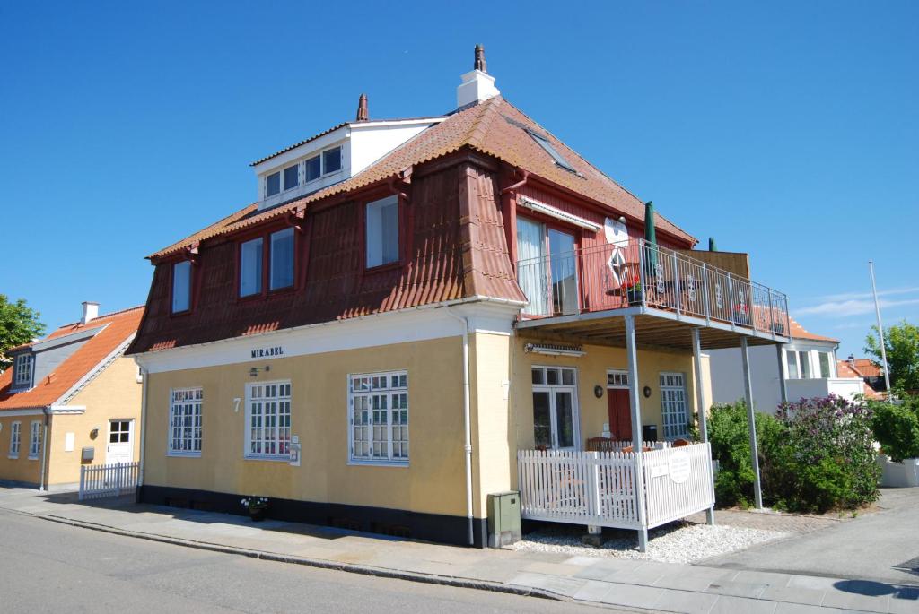 a large yellow house with a balcony on a street at Skagen Room in Skagen