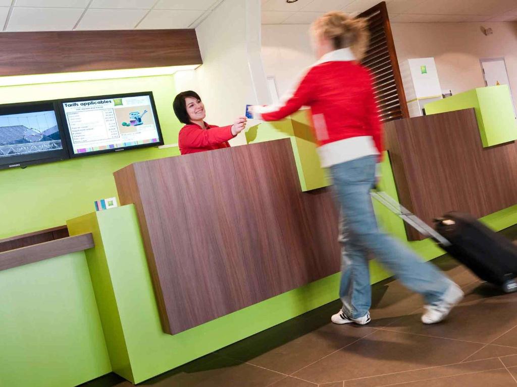 a woman is standing at a counter in an airport at ibis Styles Saint Dizier in Saint-Dizier