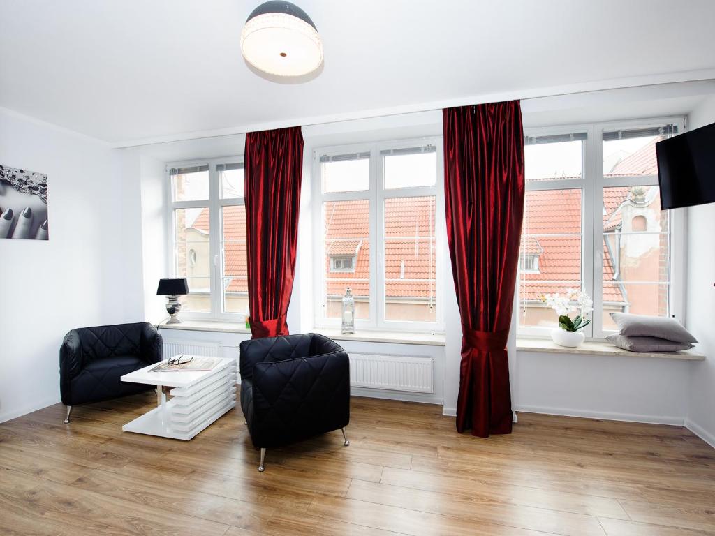 a living room with red curtains and a table and chairs at Apartament 52 Old Town in Gdańsk