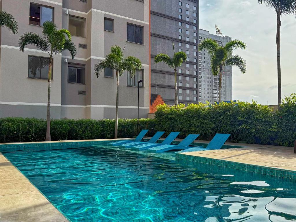 a swimming pool with blue lounge chairs and palm trees at Franklin Studio Prime Rio Energy - Piscina, Sauna, Academia in Rio de Janeiro