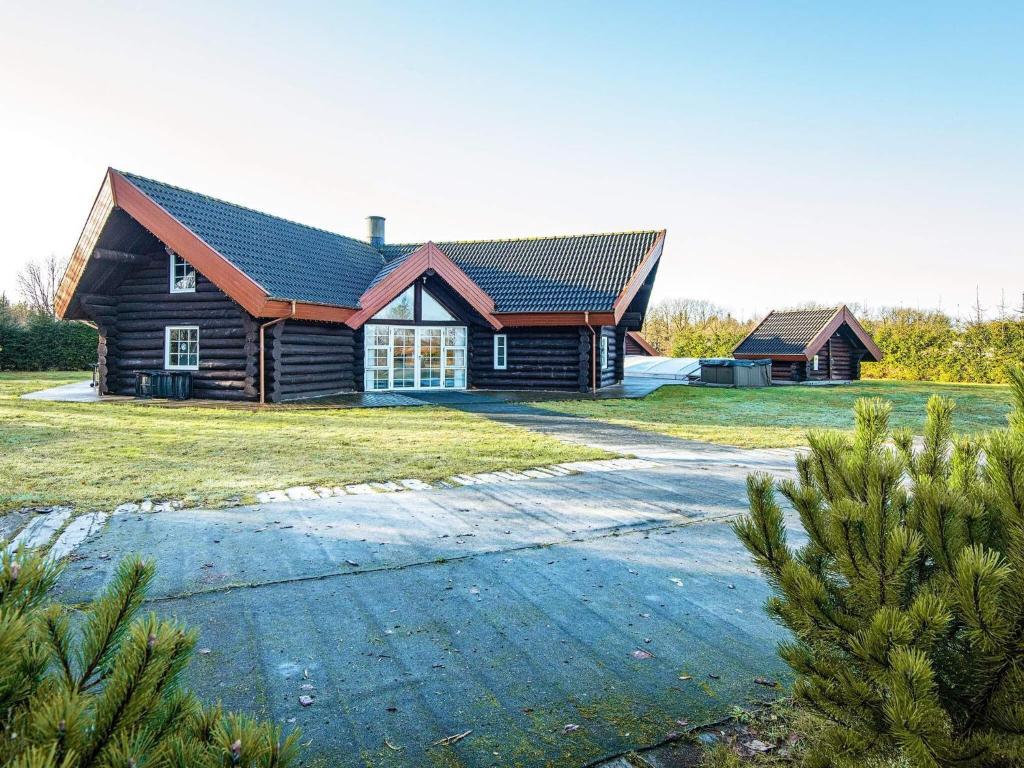 a log house with a driveway in front of it at Holiday home with pool in Ansager in Ansager