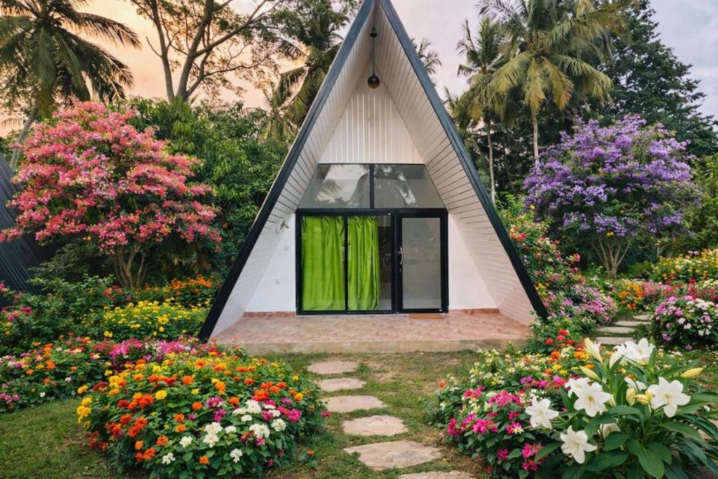 a small house in a garden with flowers at Velora Resort in Udawalawe