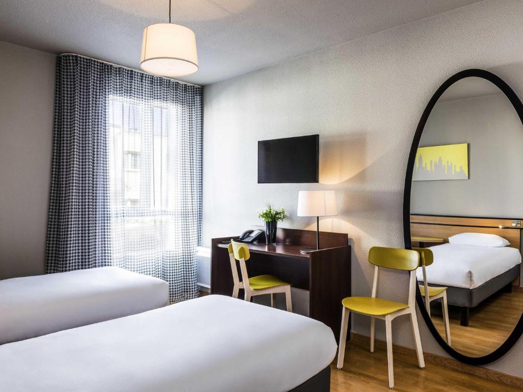 a hotel room with two beds and a mirror at Aparthotel Adagio Access Paris Vanves - Porte de Châtillon in Vanves