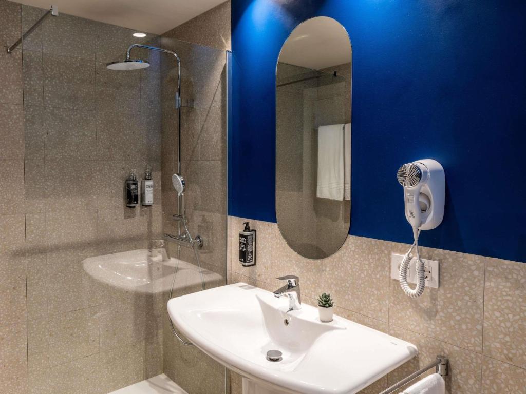 ein Badezimmer mit Waschbecken, Dusche und Spiegel in der Unterkunft Ibis Styles Zaragoza Centro in Saragossa