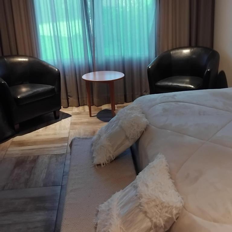 a bedroom with two chairs and a bed and a table at VICTORIA BED and BREAKFAST 1 A 3KM AEROPUERTO EZEIZA in Ezeiza