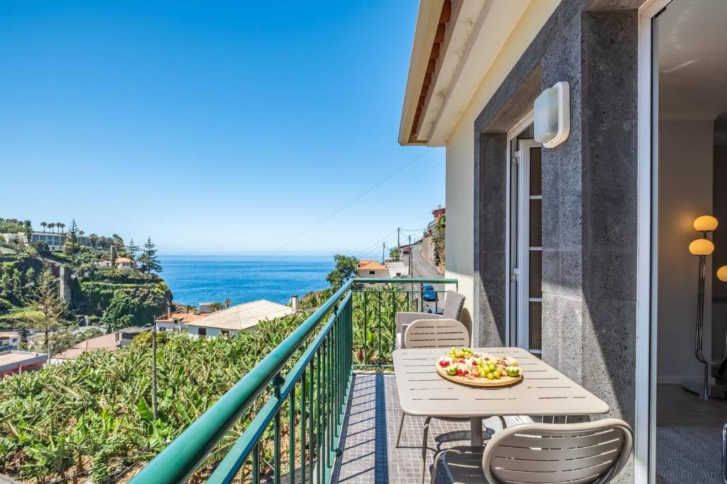 a balcony with a table and chairs and the ocean at Sunlit Apartment with Balcony & Atlantic Views in Ponta do Sol