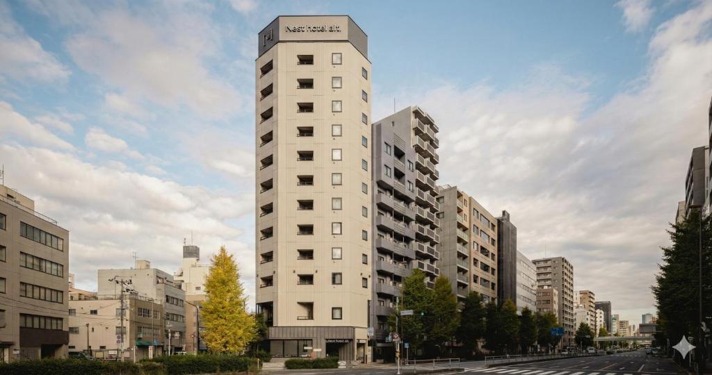 a tall white apartment building in a city at Nesthotel alt Kuramae Station in Tokyo