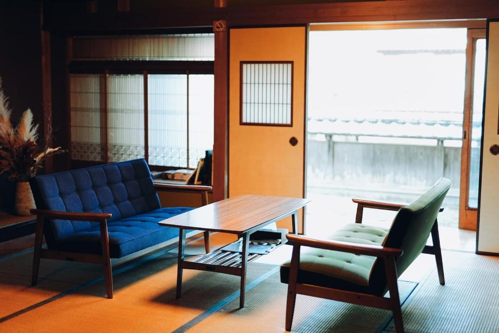 a living room with a blue couch and a table and chairs at Kumano Base in Tanabe