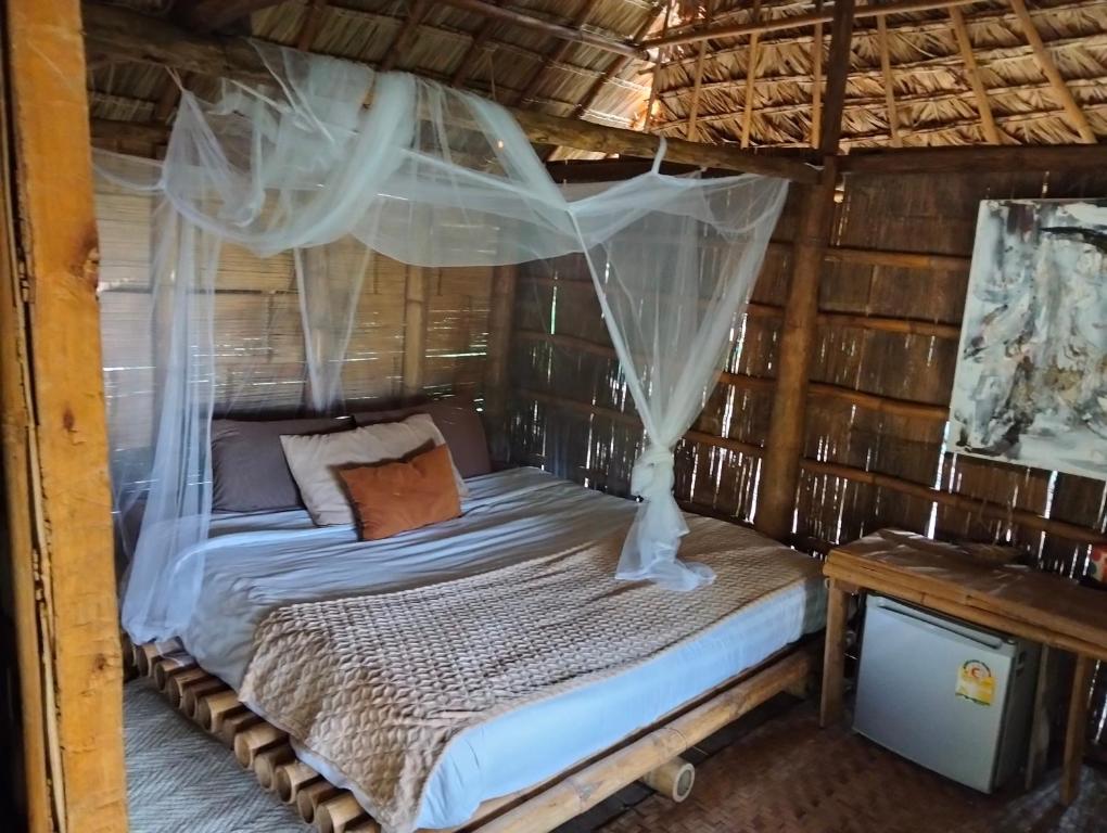 a bed with mosquito netting in a wooden cabin at ecolodge khamu homestay guesthouse in Ban Pak Ing