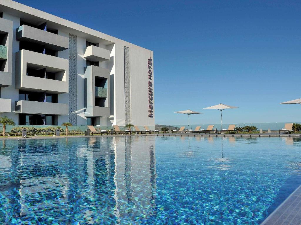 a hotel with a swimming pool in front of a building at Mercure Nador Rif in Nador