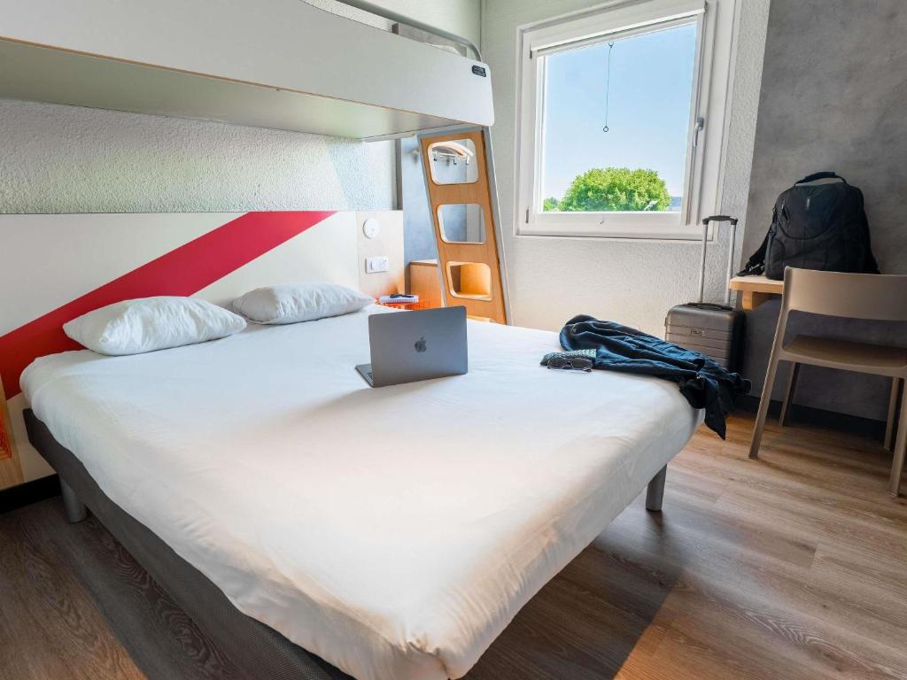 a bedroom with a bed with a laptop on it at ibis budget Strasbourg Sud Illkirch in Geispolsheim