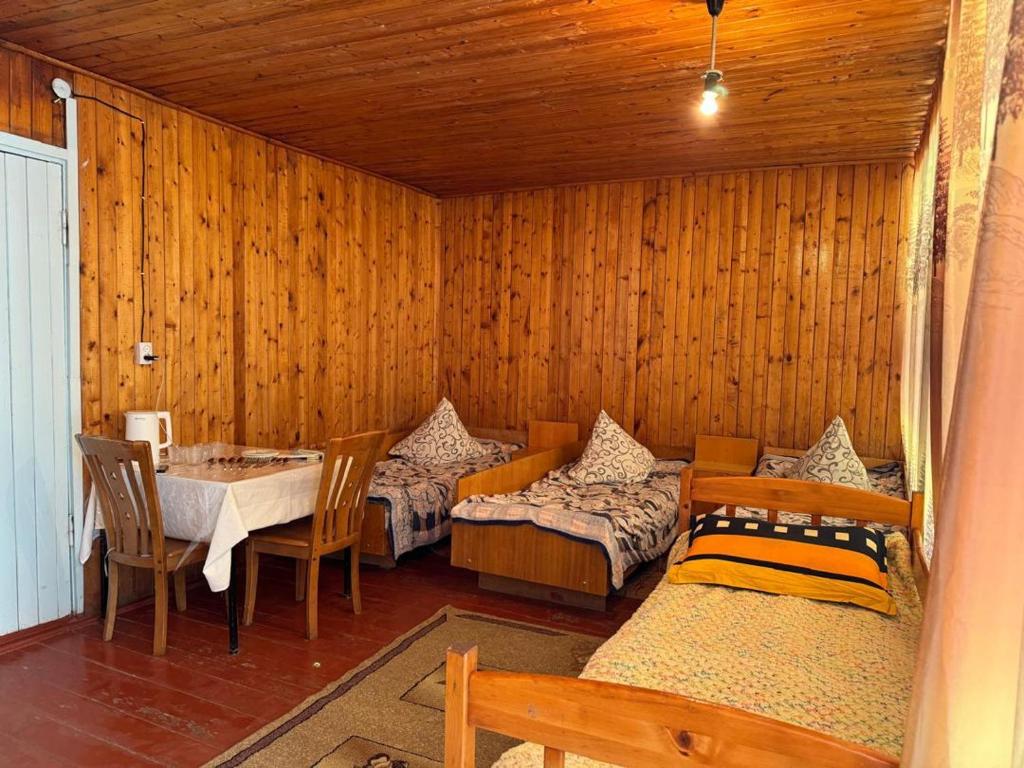 a room with two beds and a table and chairs at Хостел 9 коттедж in Cholpon-Ata