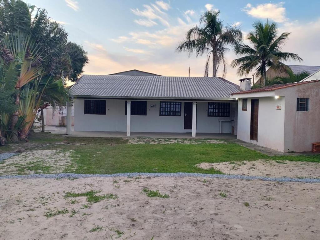 a white house with palm trees in front of it at Beira Mar Pontal do Sul in Pontal do Paraná