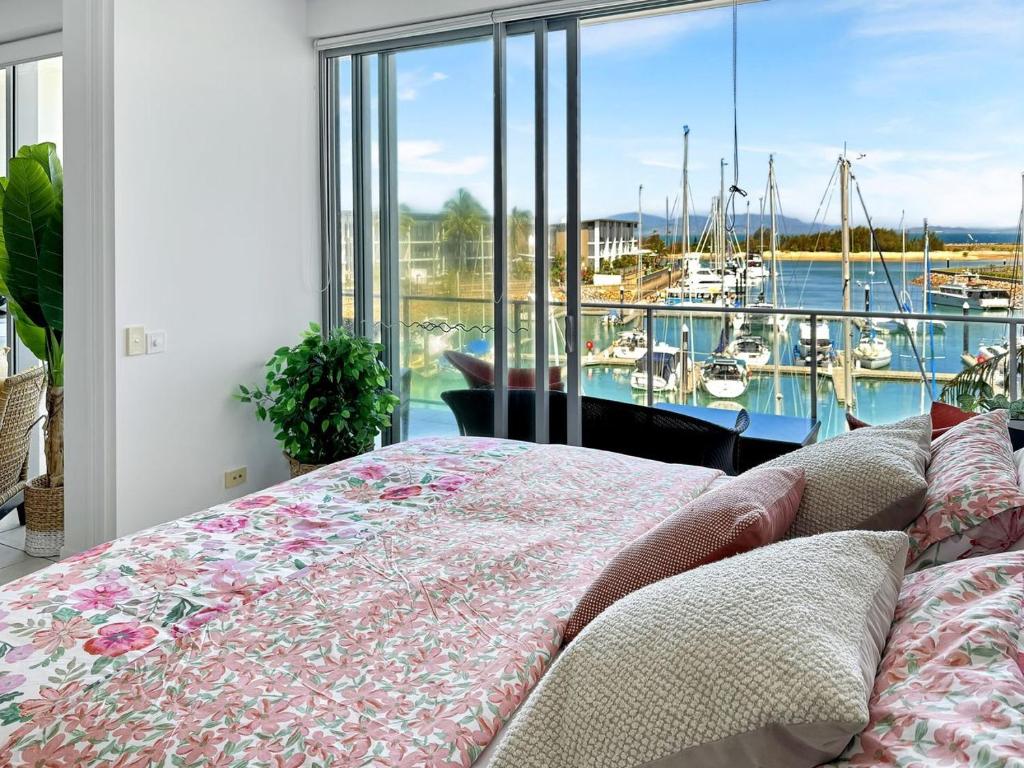 a bedroom with a bed and a view of a marina at Blue on Blue Apartment 933 in Nelly Bay