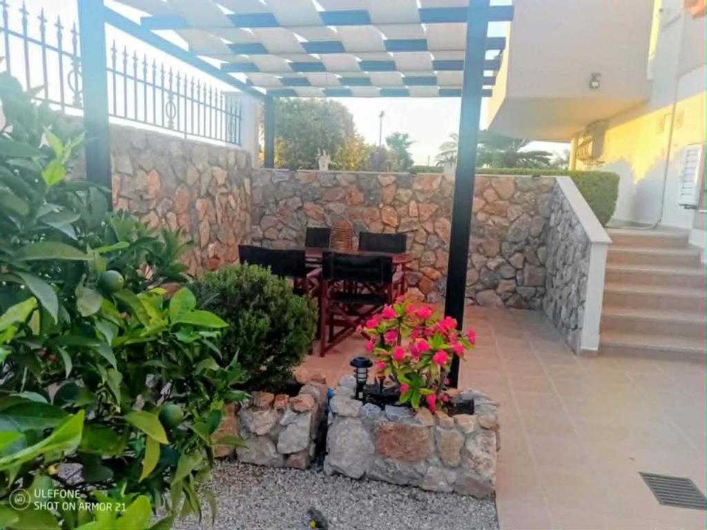 a patio with a stone wall and a table and flowers at Timeless Memories Studio in Zipárion