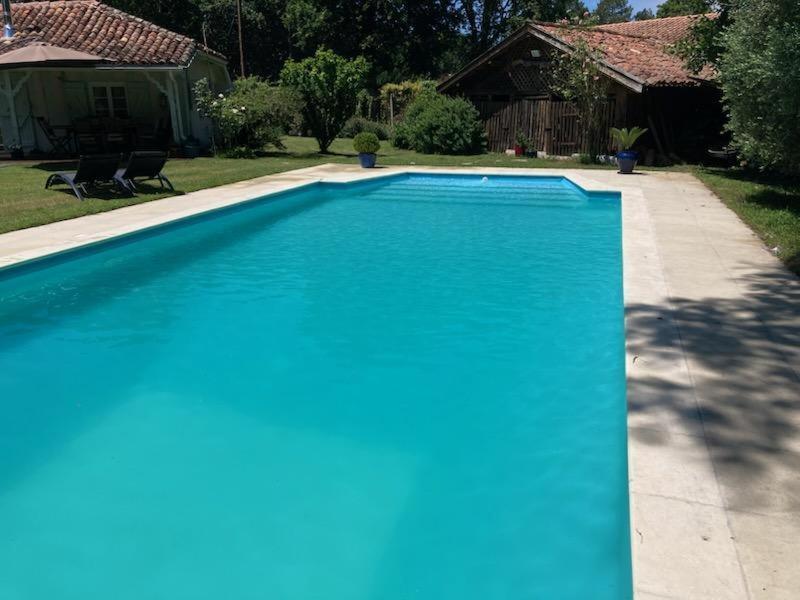 a blue swimming pool in a yard with a house at Bois sauvage in Parentis-en-Born