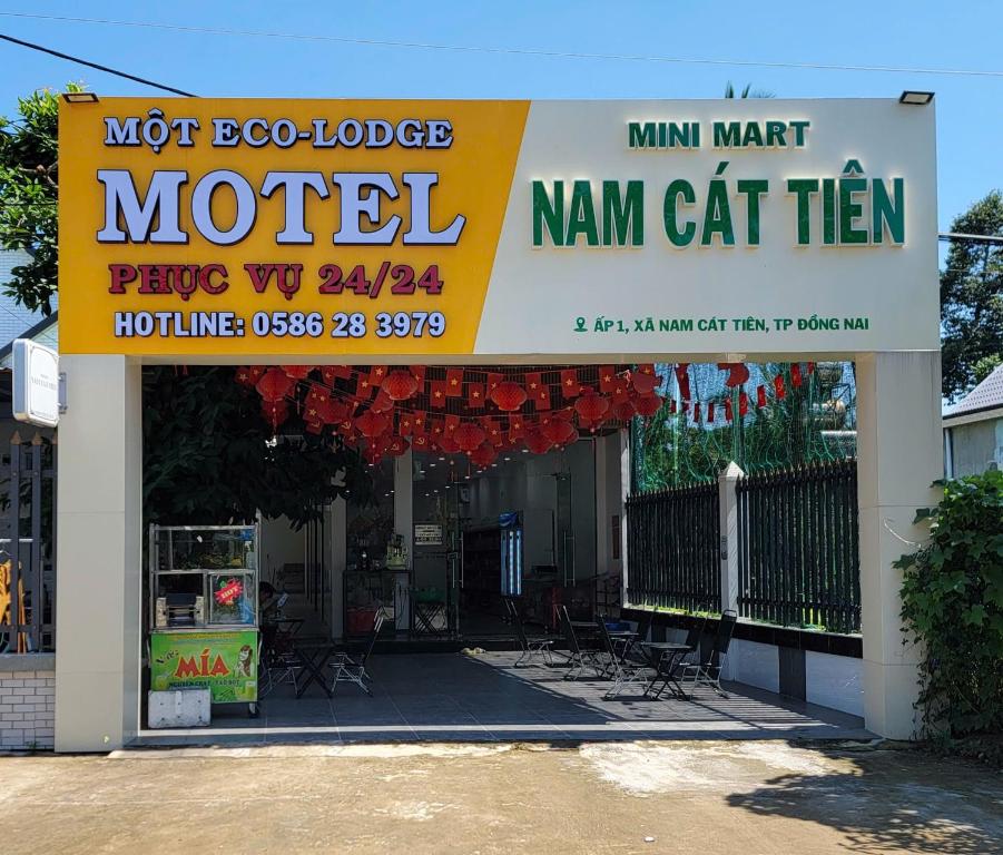 a sign for a motel with chairs and a building at Một Eco-Lodge in Tân Phú