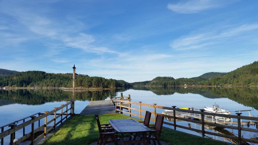 a dock with a table and a boat on a lake at Nesheim Cabin-By-The-Sea in Øygarden