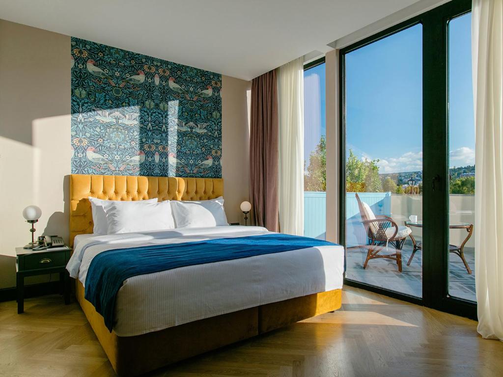 a bedroom with a large bed and a large window at Museum Hotel in Tbilisi City